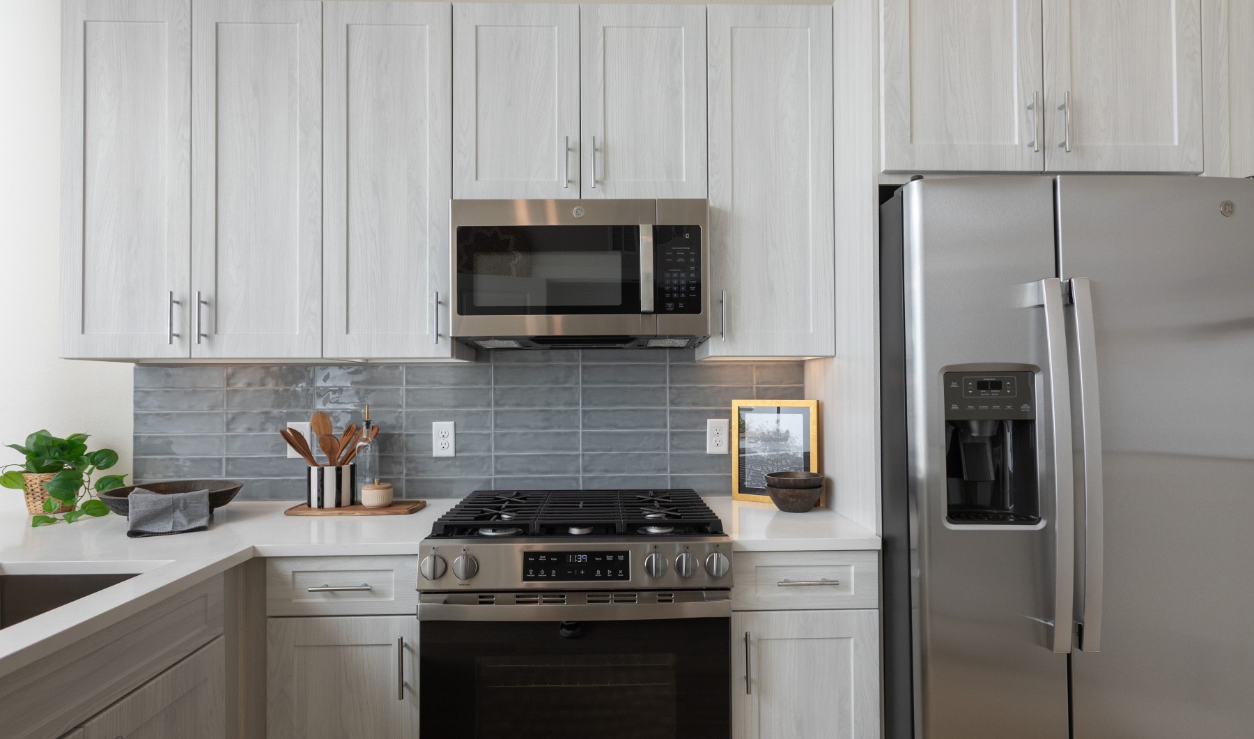 A modern kitchen featuring a stainless steel refrigerator and a sleek stove, with cabinets and countertops visible.