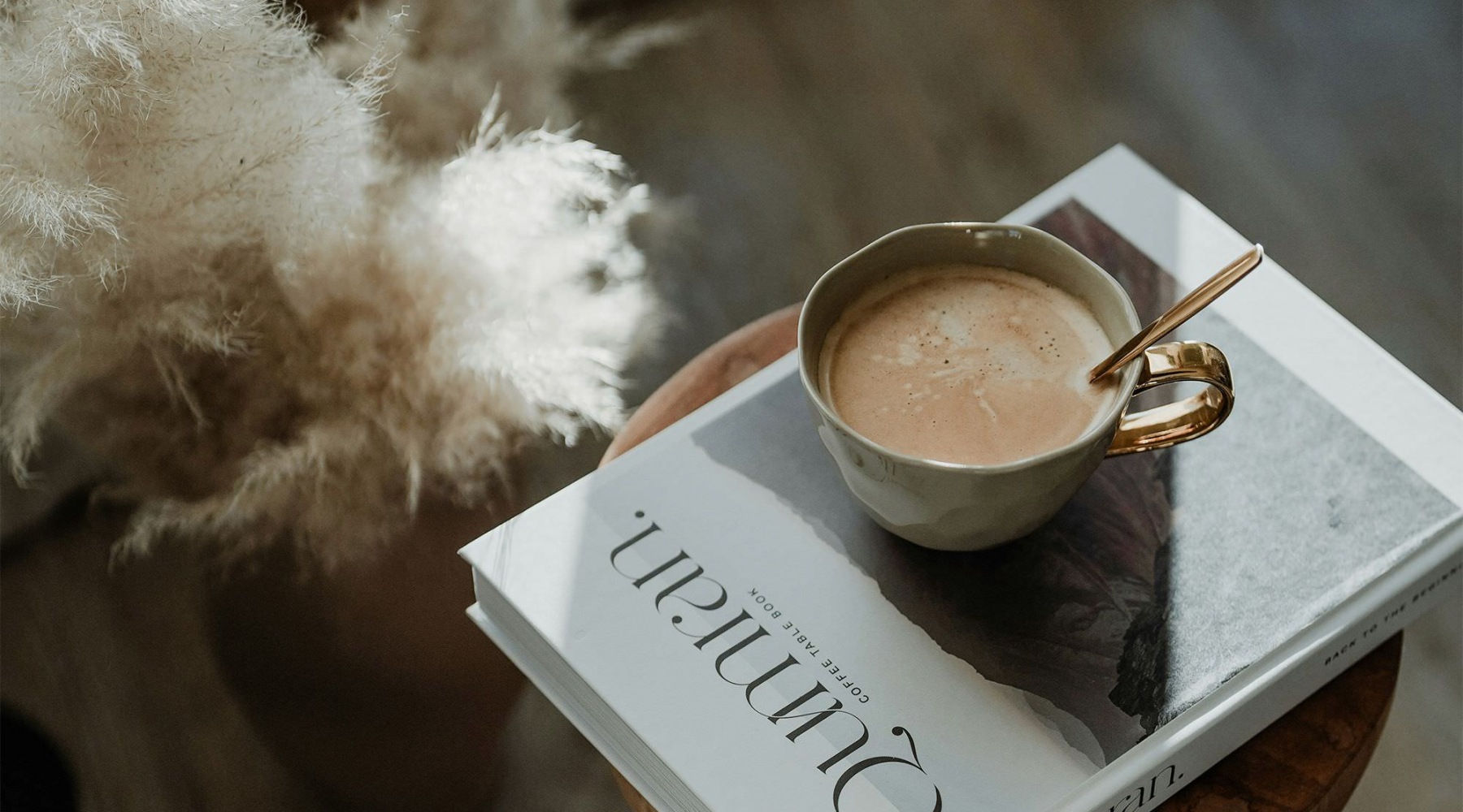 a cup of coffee on a book on a stool in a living room